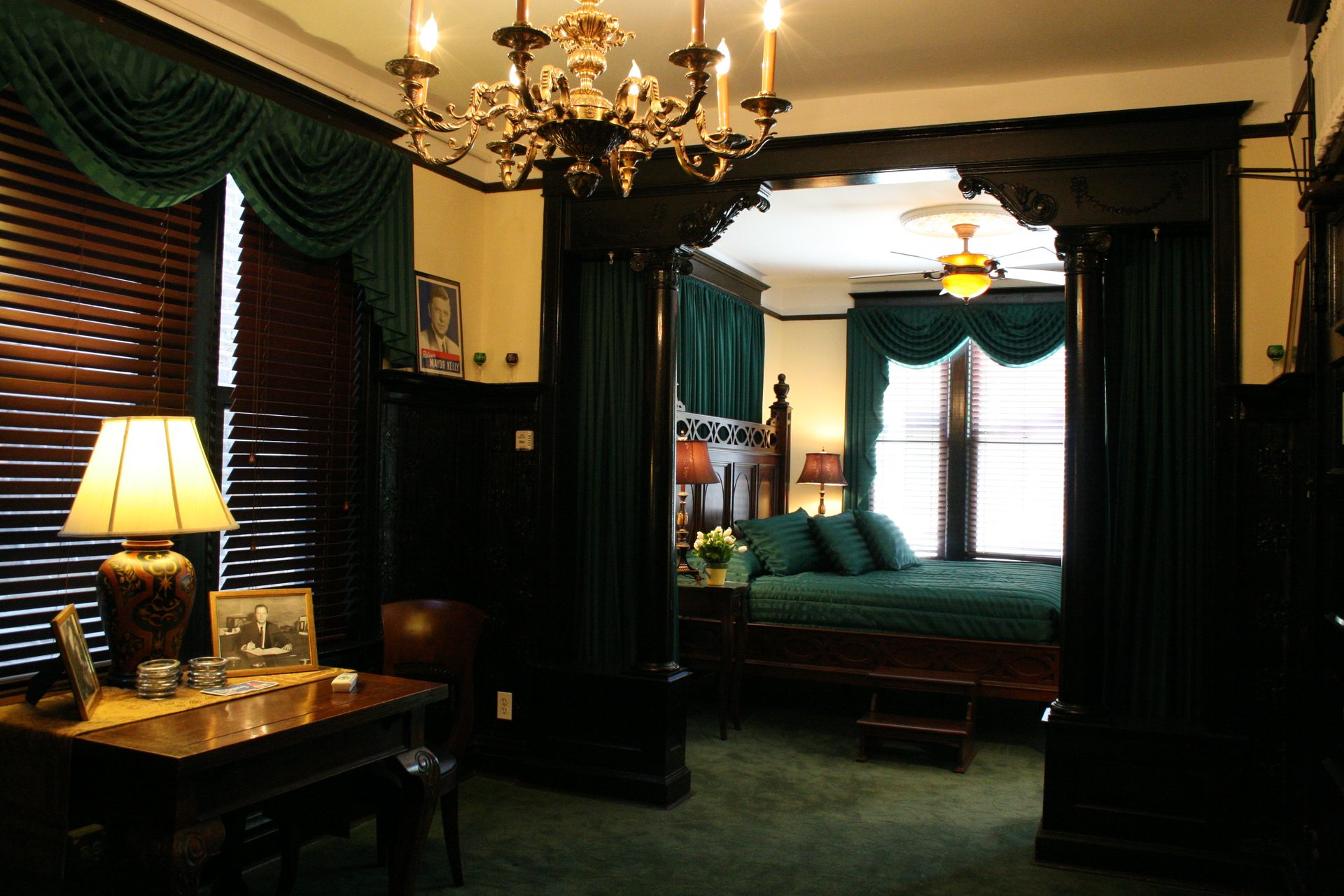 The Mayors' Suite — a green-draped four-poster bed beneath a brass chandelier