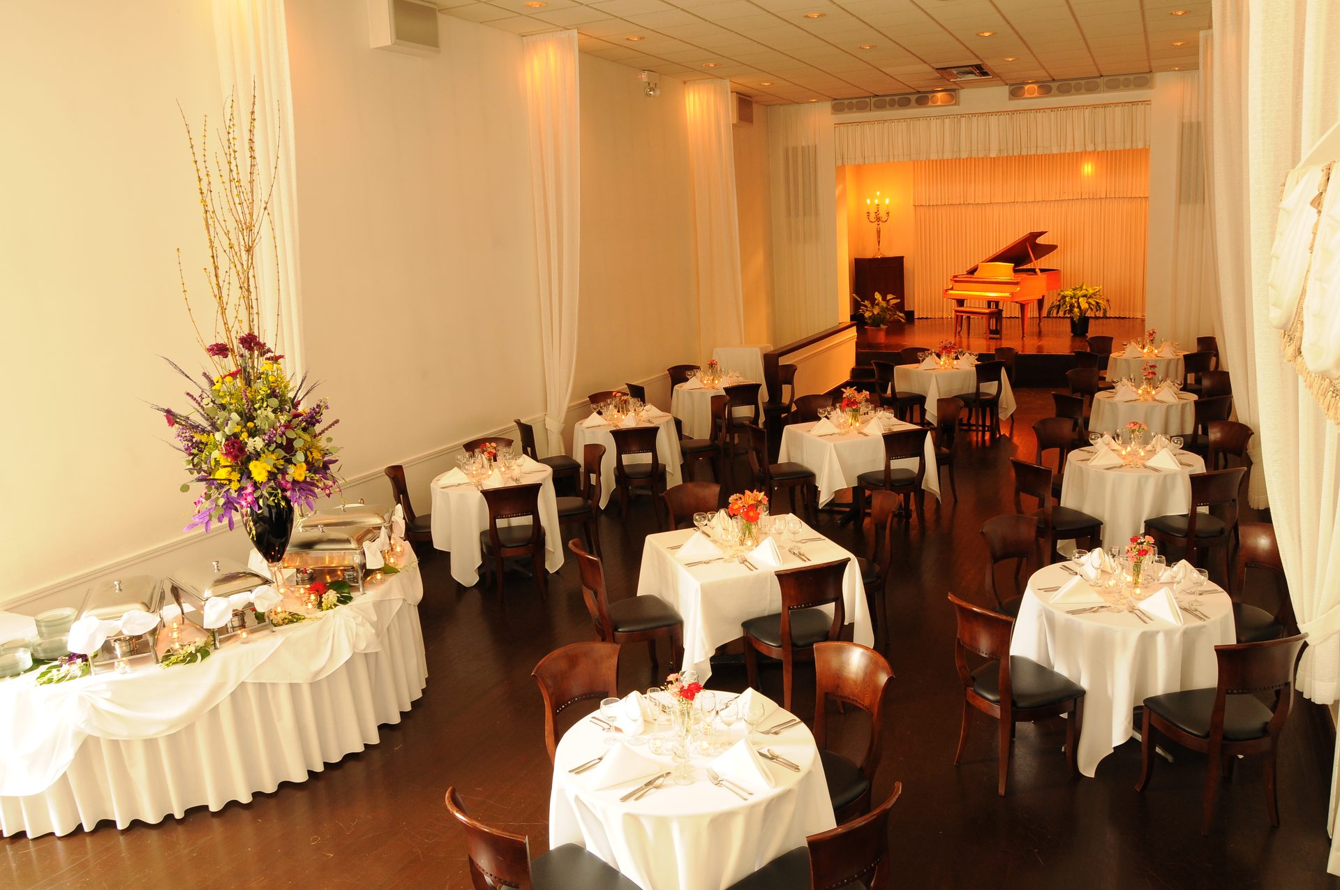 The Old Eagle Room at The Polo Inn — white-linen tables set before a grand piano on the stage